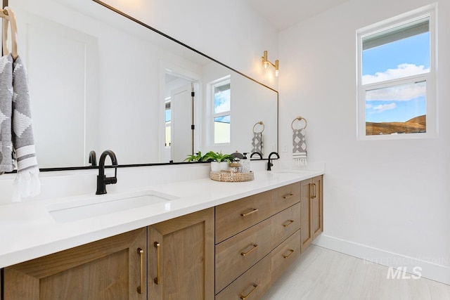 bathroom featuring plenty of natural light, a sink, and baseboards