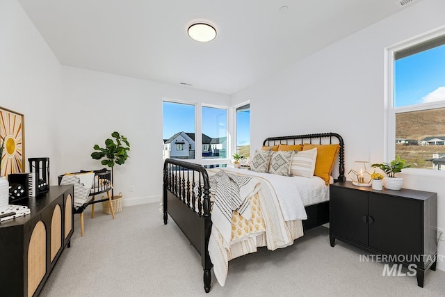 bedroom with light carpet, multiple windows, and baseboards