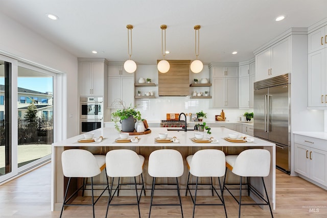 kitchen with open shelves, stainless steel appliances, light countertops, decorative backsplash, and a sink