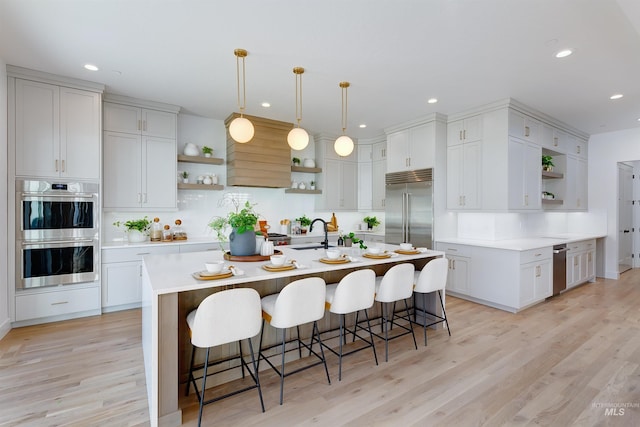 kitchen featuring light wood-style flooring, appliances with stainless steel finishes, open shelves, and light countertops