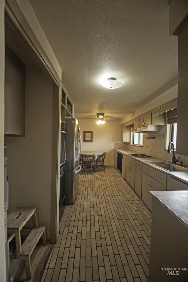 104 Friendship Ln, Council, ID 83612 - kitchen featuring stainless steel appliances, a ceiling fan, brick patterned floors, under cabinet range hood, and backsplash