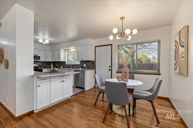 kitchen with hanging light fixtures, white cabinets, and appliances with stainless steel finishes