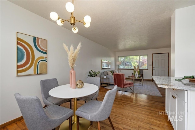 dining space with hardwood / wood-style floors, a notable chandelier, and a textured ceiling