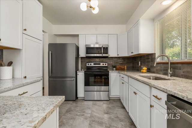 kitchen with sink, stainless steel appliances, light stone countertops, white cabinets, and decorative backsplash