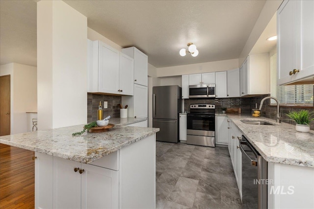 kitchen featuring light stone countertops, stainless steel appliances, sink, and white cabinets