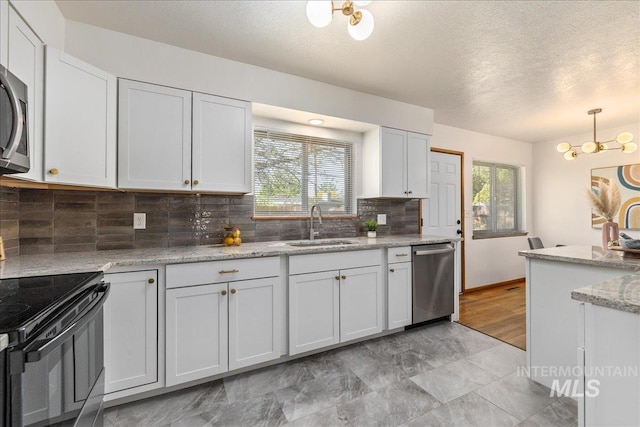 kitchen with sink, dishwasher, hanging light fixtures, white cabinets, and black / electric stove