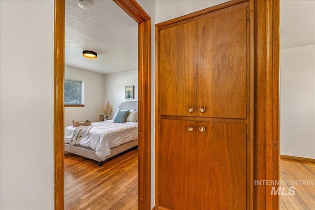 bedroom with a textured ceiling and light hardwood / wood-style flooring