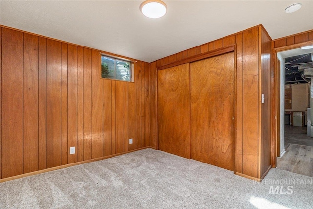 carpeted empty room featuring wood walls