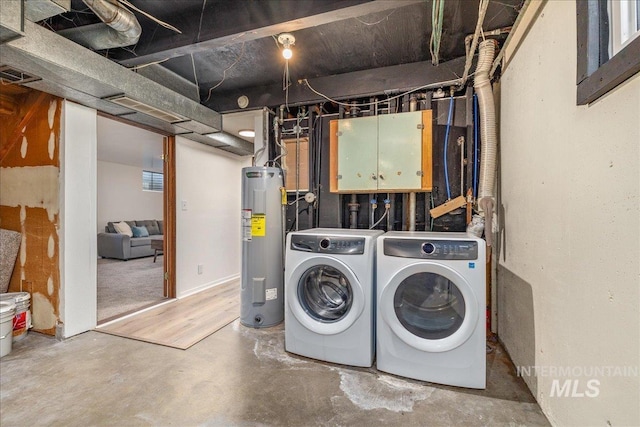 clothes washing area with washer and dryer, cabinets, and water heater