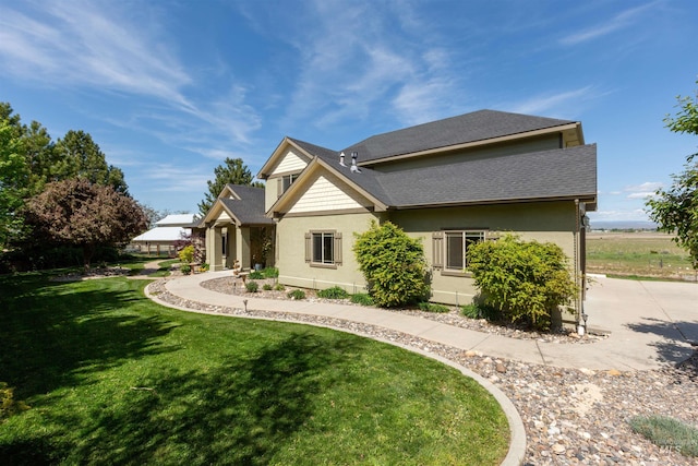 rear view of property with a lawn, a shingled roof, stucco siding, and concrete driveway