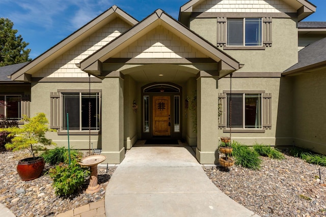 property entrance featuring roof with shingles and stucco siding