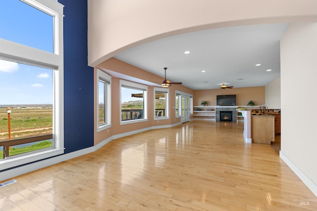unfurnished living room with recessed lighting, a ceiling fan, arched walkways, and a tile fireplace