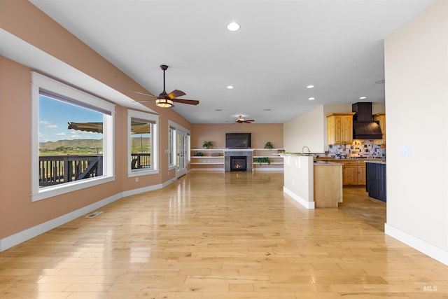 kitchen featuring a ceiling fan, a tile fireplace, custom exhaust hood, open floor plan, and recessed lighting