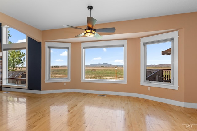 empty room featuring visible vents, baseboards, ceiling fan, and light wood-type flooring