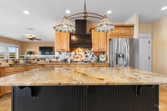 kitchen with appliances with stainless steel finishes, a breakfast bar, a sink, light tile patterned floors, and tasteful backsplash