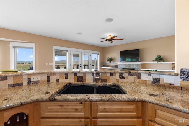 kitchen featuring a sink, a ceiling fan, and light stone countertops
