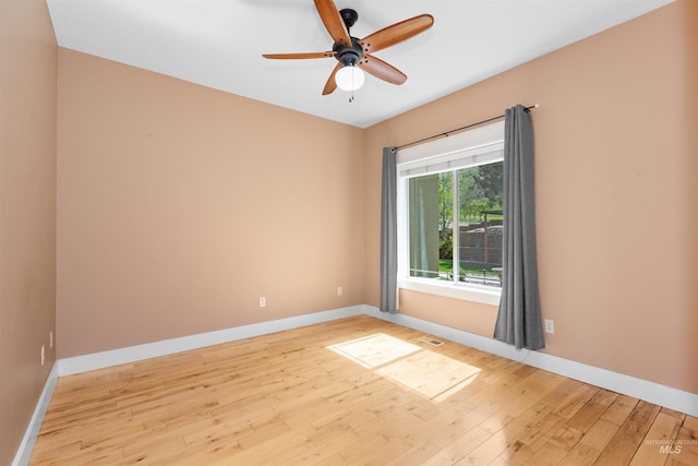 spare room featuring baseboards, a ceiling fan, wood finished floors, and visible vents