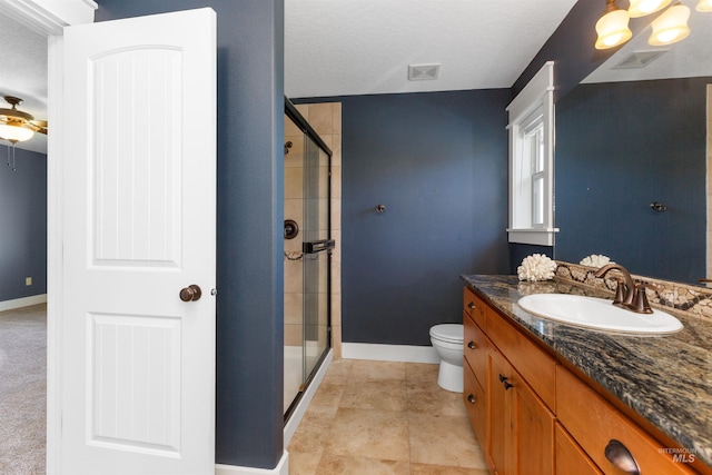 bathroom with vanity, toilet, baseboards, visible vents, and a stall shower