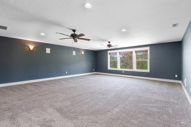 spare room with carpet flooring, ceiling fan, a textured ceiling, baseboards, and visible vents