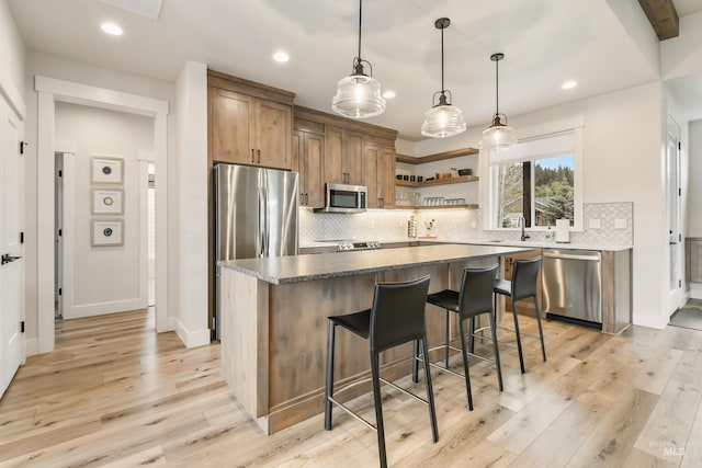 1112 Mos Way, Mccall, ID 83638 - kitchen with stainless steel appliances, open shelves, light wood-type flooring, a kitchen island, and tasteful backsplash