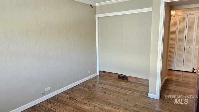 unfurnished bedroom with wood finished floors, baseboards, and crown molding