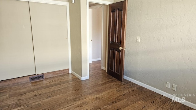 unfurnished bedroom with wood finished floors, a closet, and baseboards