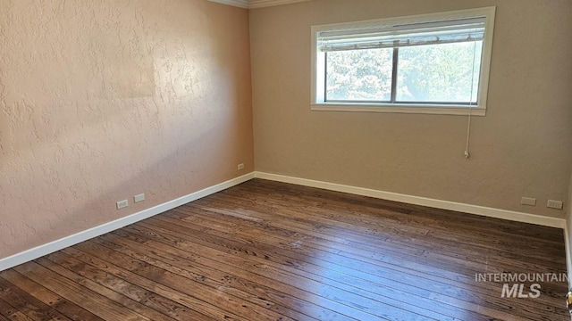 unfurnished room featuring dark wood finished floors, baseboards, and crown molding
