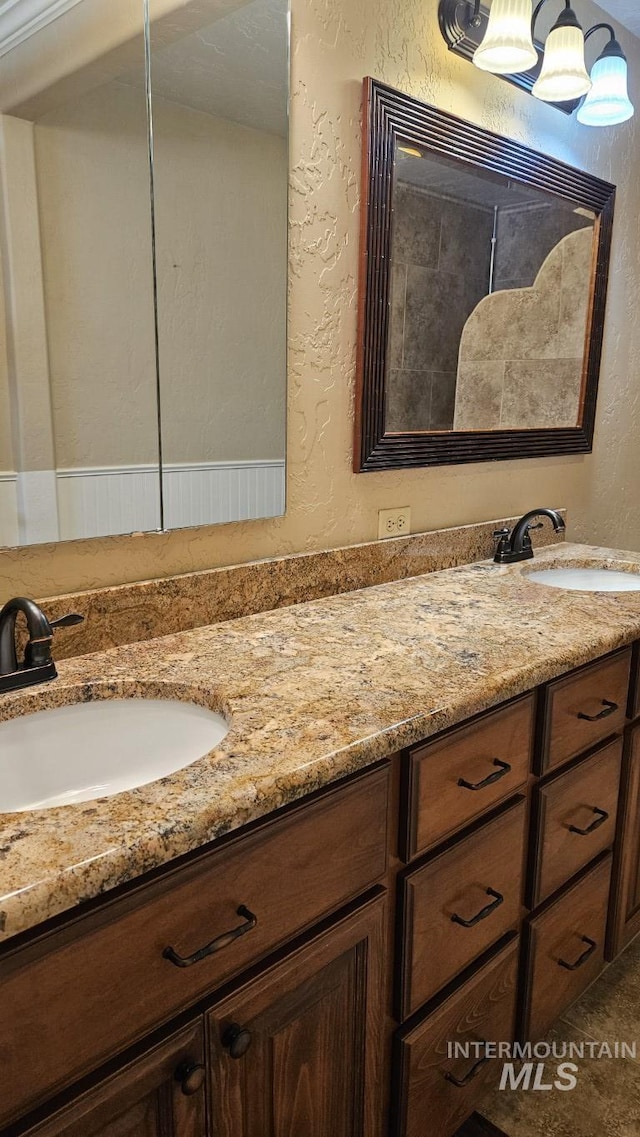 full bath with a textured wall and double vanity