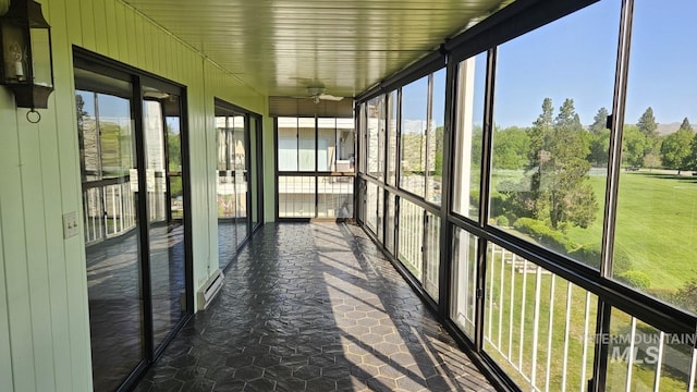 unfurnished sunroom featuring ceiling fan and a baseboard heating unit