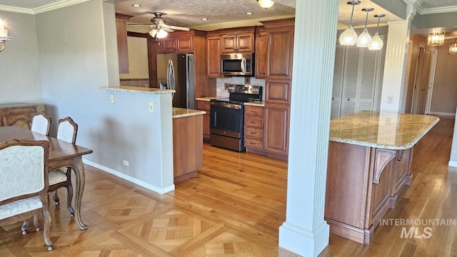 kitchen with stainless steel appliances, a ceiling fan, brown cabinets, light stone countertops, and ornamental molding