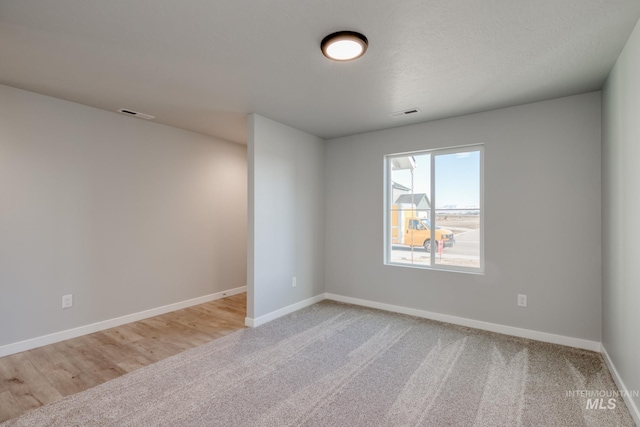 spare room with visible vents, baseboards, and light carpet