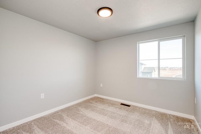 carpeted empty room with visible vents and baseboards