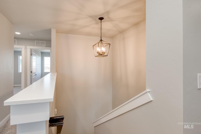 stairway with a notable chandelier, visible vents, and baseboards