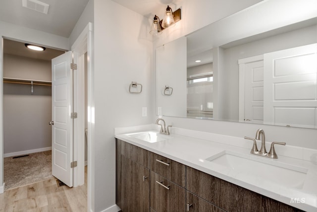 full bath featuring visible vents, wood finished floors, a walk in closet, and a sink