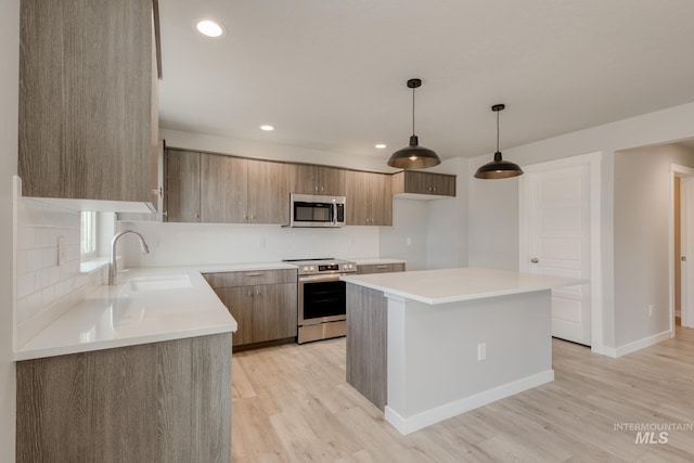 kitchen featuring light wood finished floors, a sink, appliances with stainless steel finishes, tasteful backsplash, and a center island