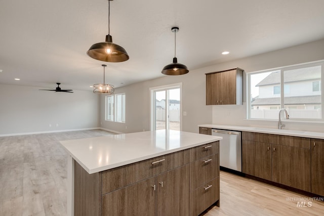 kitchen with a sink, plenty of natural light, light wood-style flooring, and stainless steel dishwasher