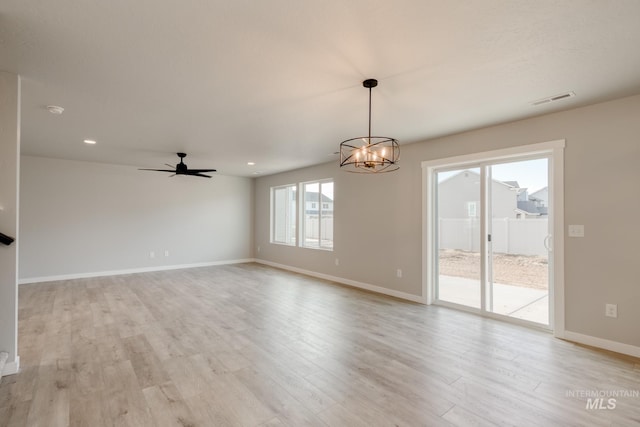 spare room featuring light wood-type flooring, visible vents, ceiling fan with notable chandelier, recessed lighting, and baseboards