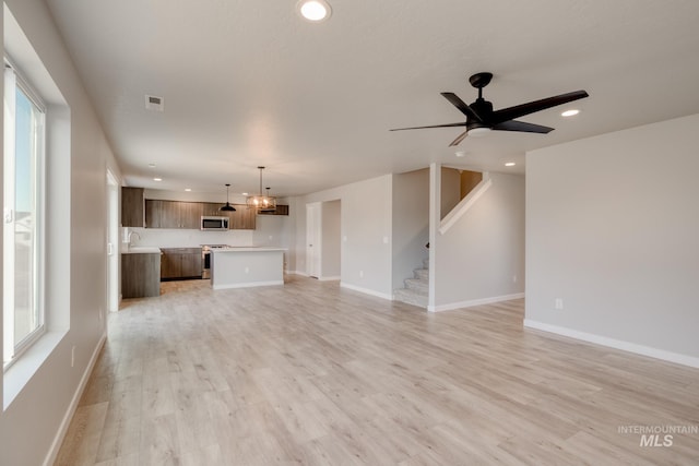 unfurnished living room featuring visible vents, baseboards, recessed lighting, light wood-style flooring, and a sink