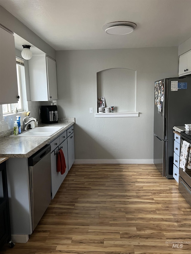 kitchen with tasteful backsplash, stainless steel appliances, sink, light hardwood / wood-style flooring, and white cabinetry