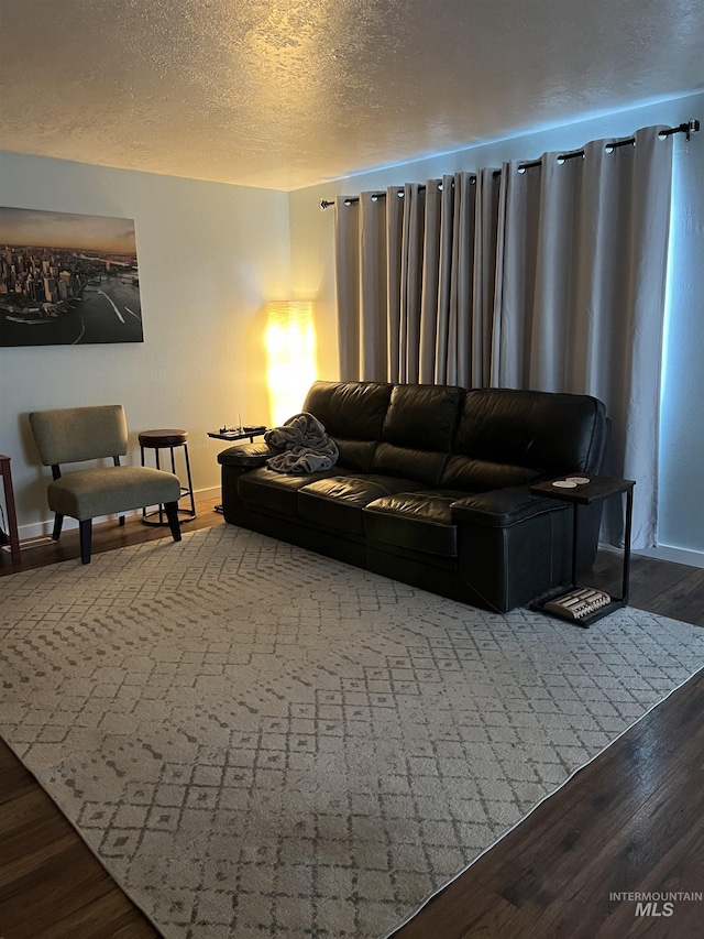 living room with a textured ceiling and dark hardwood / wood-style floors