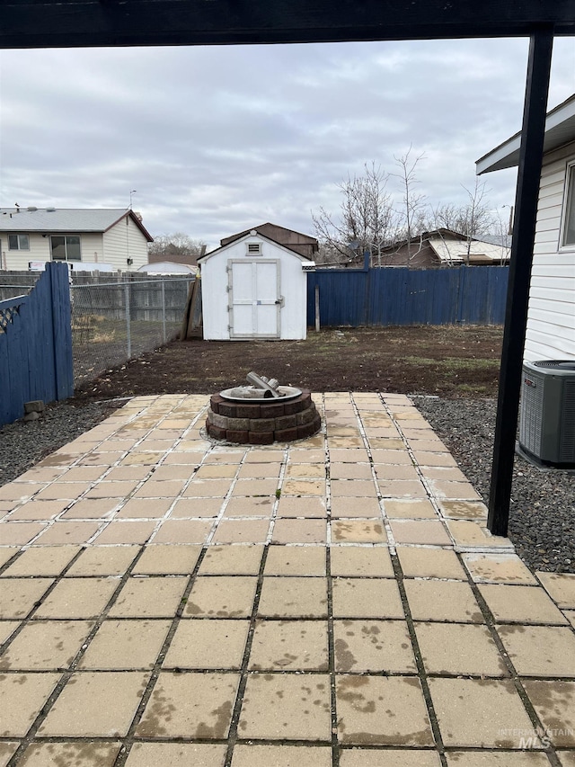 view of patio / terrace with a storage shed, central AC unit, and an outdoor fire pit