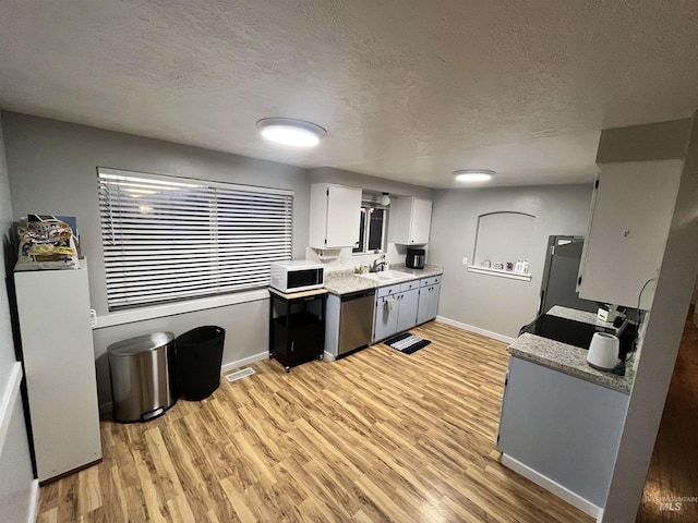 kitchen with sink, stainless steel dishwasher, a textured ceiling, light hardwood / wood-style floors, and white cabinetry