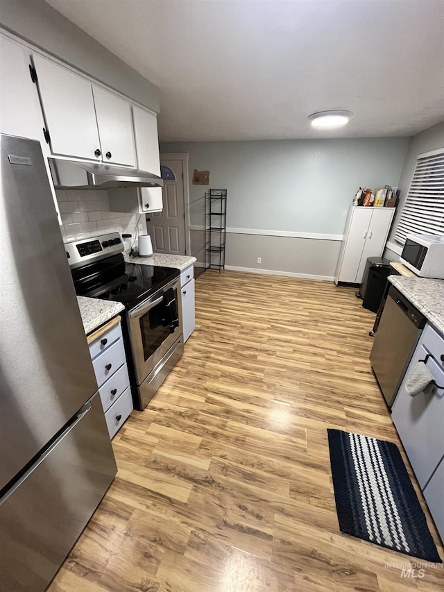 kitchen with backsplash, stainless steel appliances, white cabinetry, and light hardwood / wood-style flooring