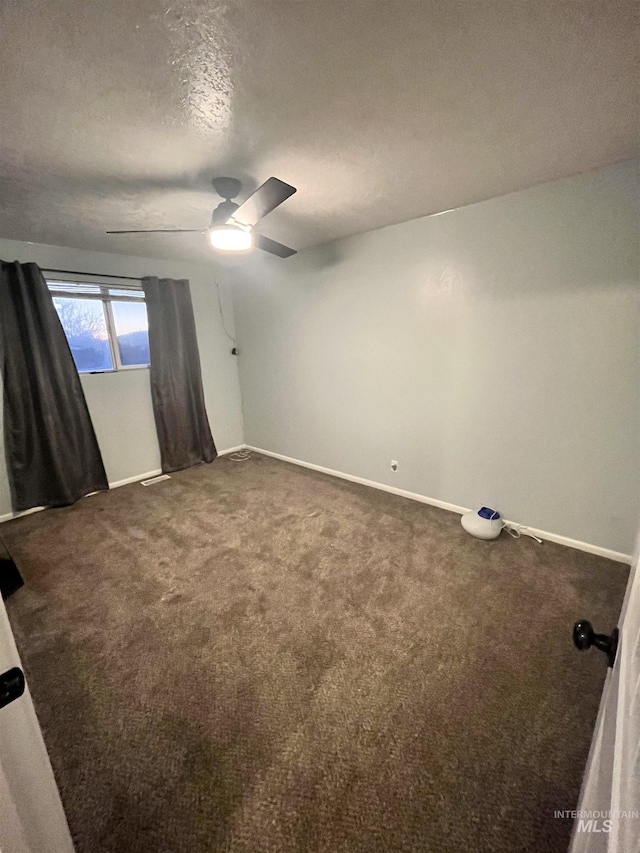 unfurnished room featuring dark colored carpet, ceiling fan, and a textured ceiling