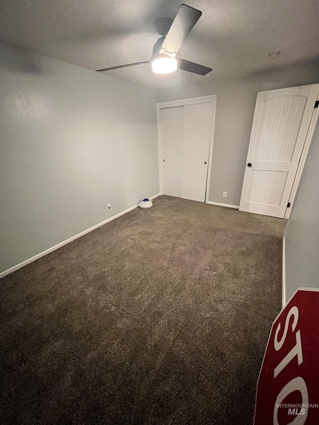 unfurnished bedroom featuring dark colored carpet, ceiling fan, and a closet