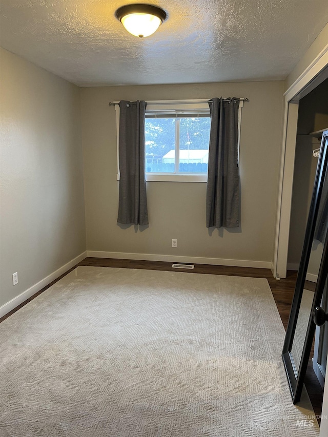 empty room with wood-type flooring and a textured ceiling