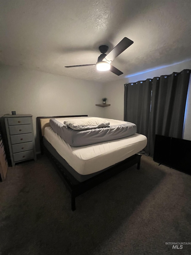 carpeted bedroom featuring ceiling fan and a textured ceiling