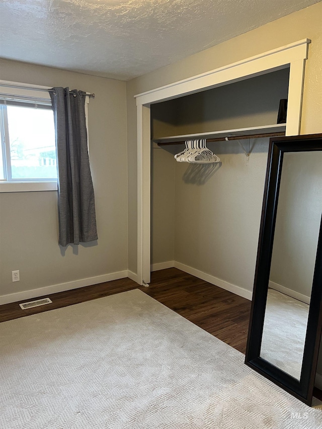 unfurnished bedroom featuring hardwood / wood-style flooring, a textured ceiling, and a closet