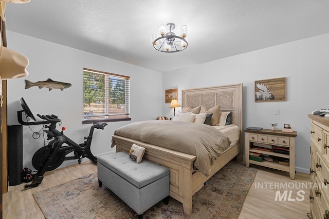 bedroom featuring light wood-type flooring and a notable chandelier