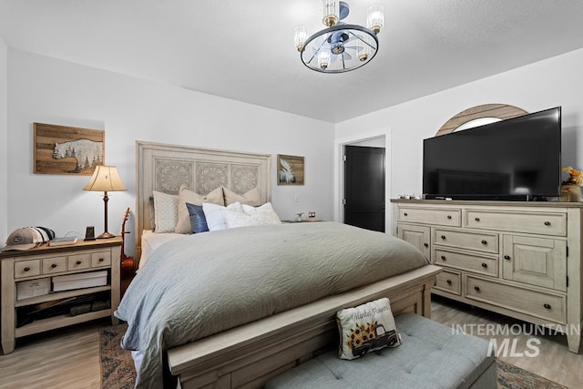 bedroom with light hardwood / wood-style flooring and a chandelier